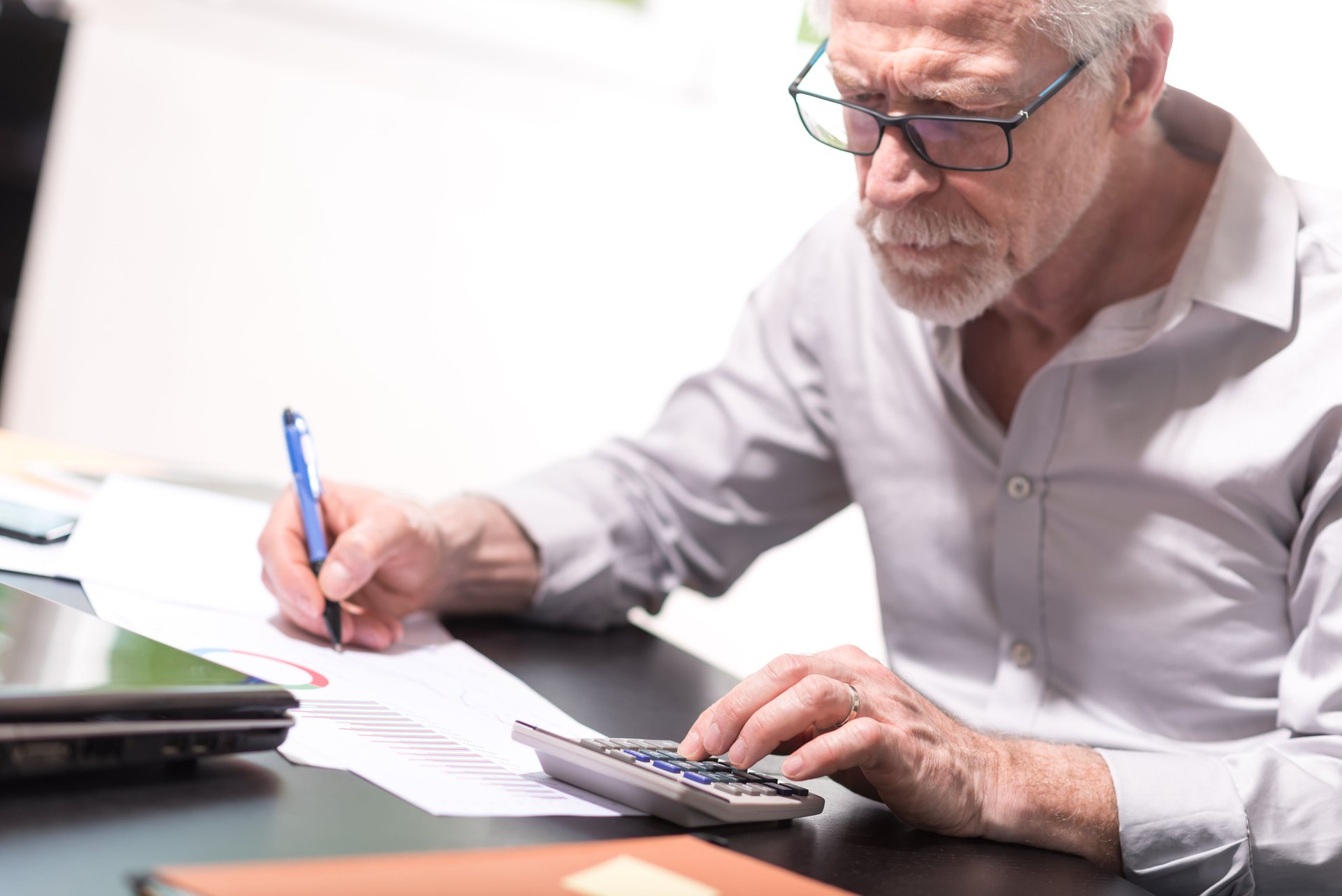 Older adult reviewing retirement calculations and financial paperwork